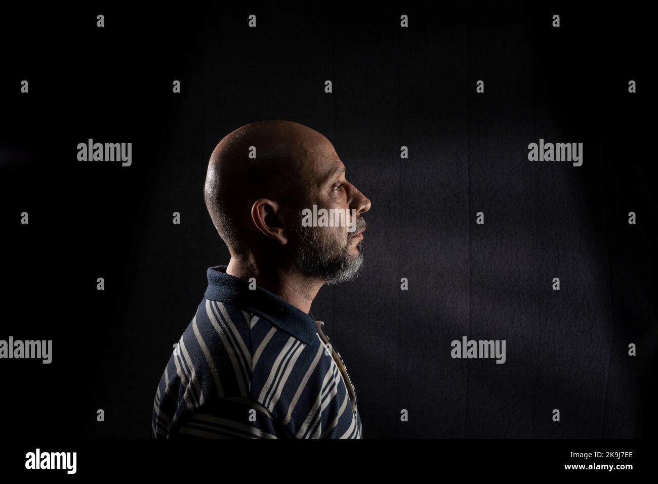 Young handsome bald man with beard wearing casual shirt over black background. Thinking worried. Thoughtful. Stock Photo