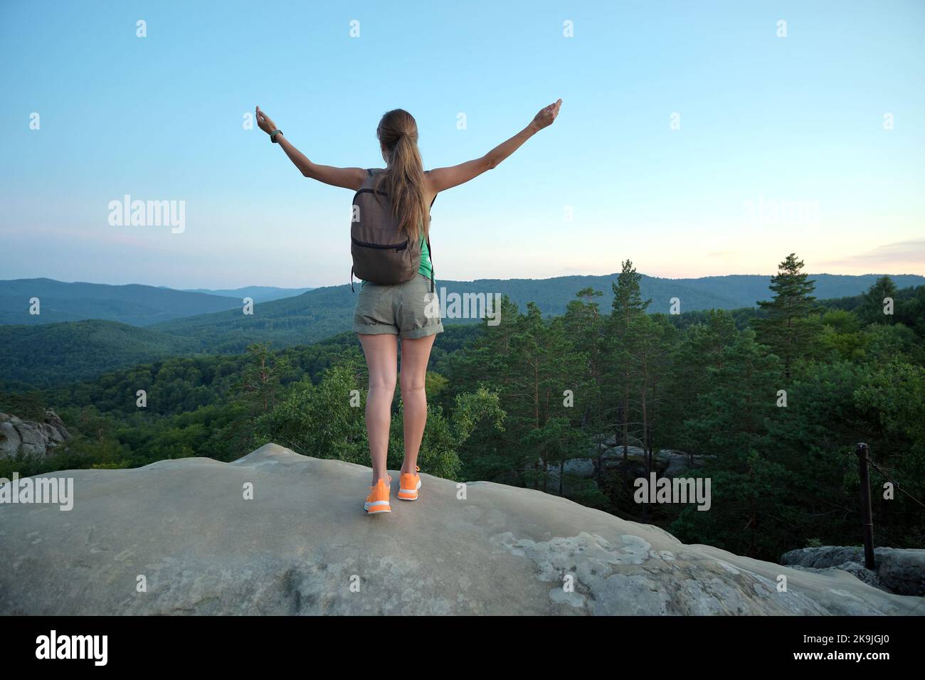 Hiker woman standing on mountain footpath raising up hands enjoying ...