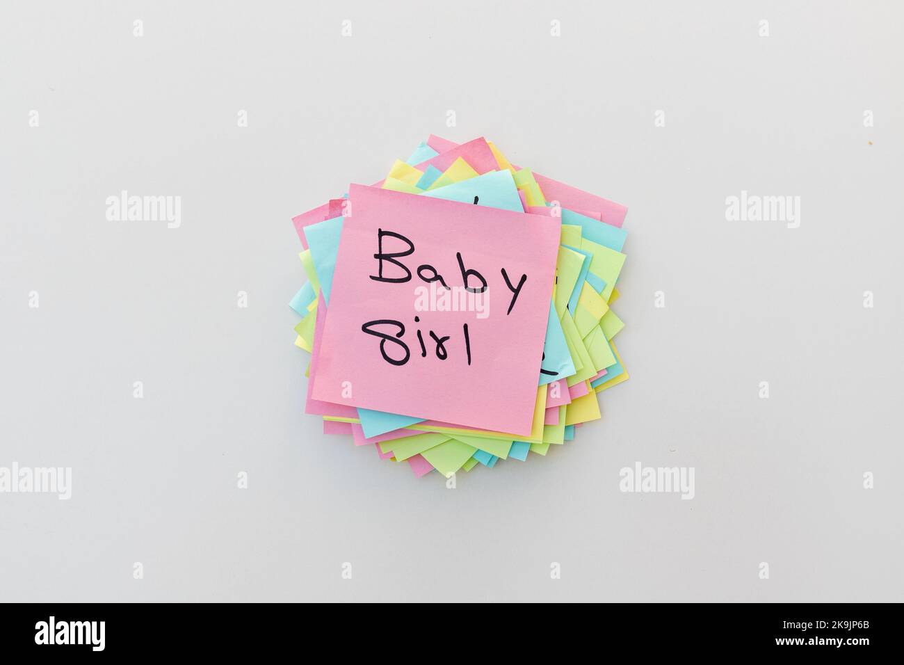 Baby girl gender reveal handwritten on a pink sticky note with white isolated background Stock Photo