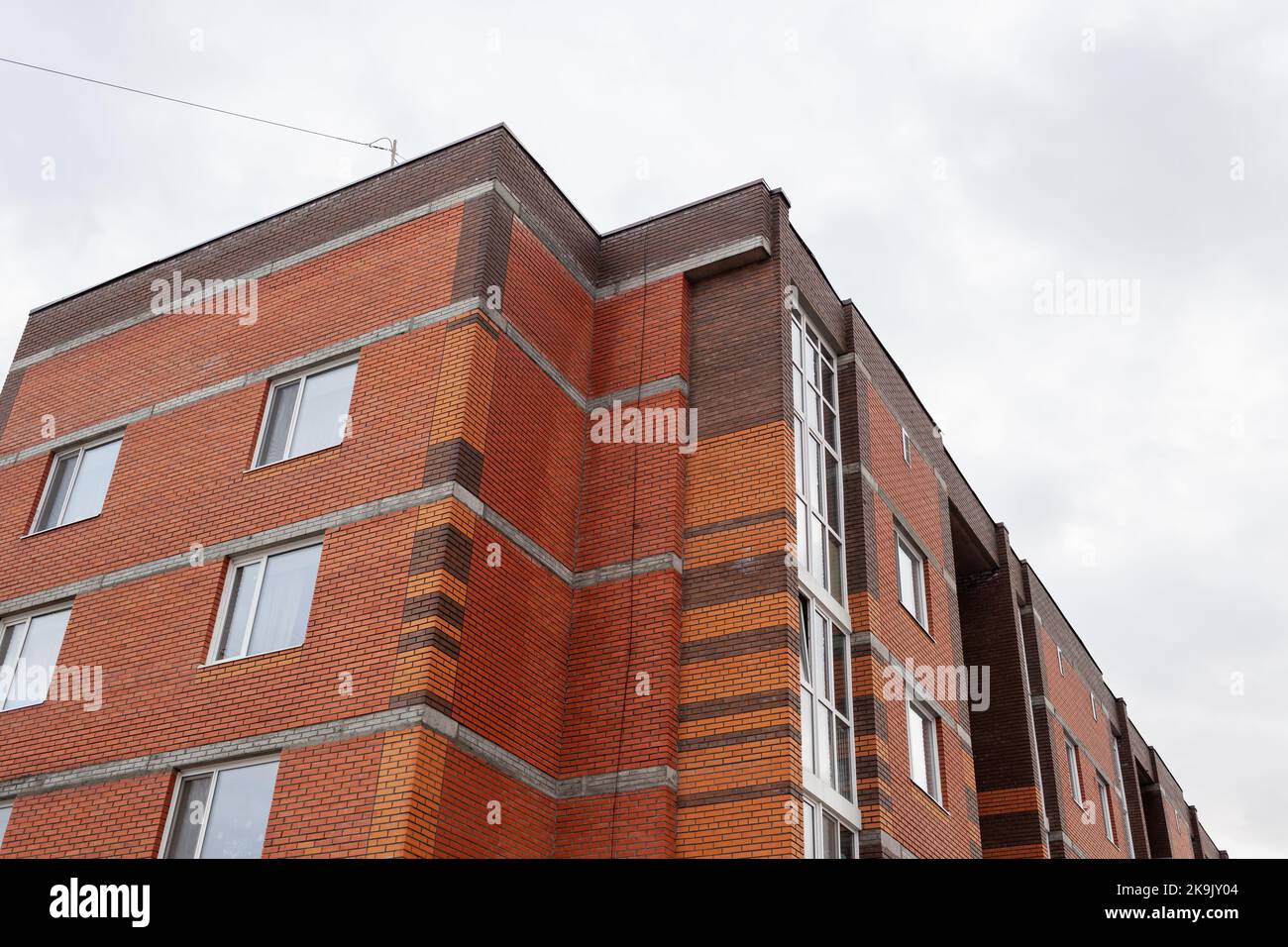 Windows of a residential multi-storey brick house. Modern buildings. The new multi-storey apartment brick building against the sky Stock Photo