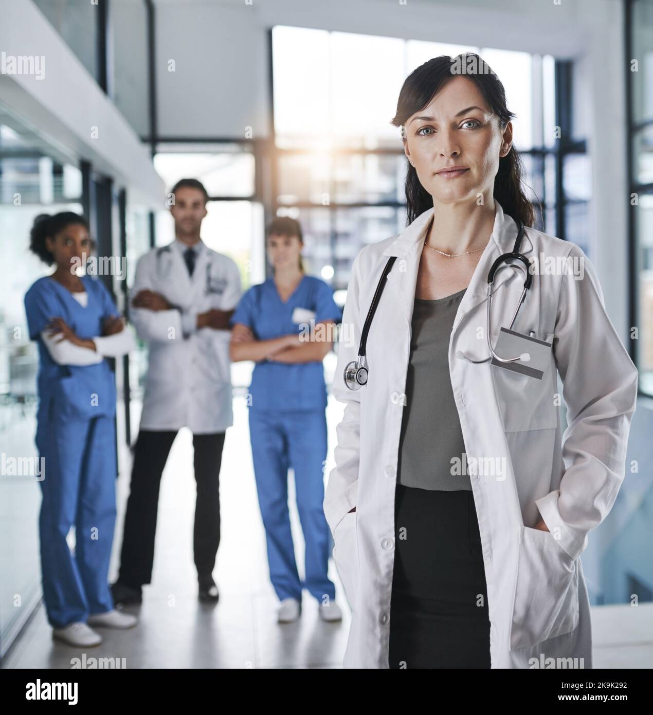 The finest in the medical field. Portrait of a confident mature doctor working in a hospital with her colleagues in the background. Stock Photo