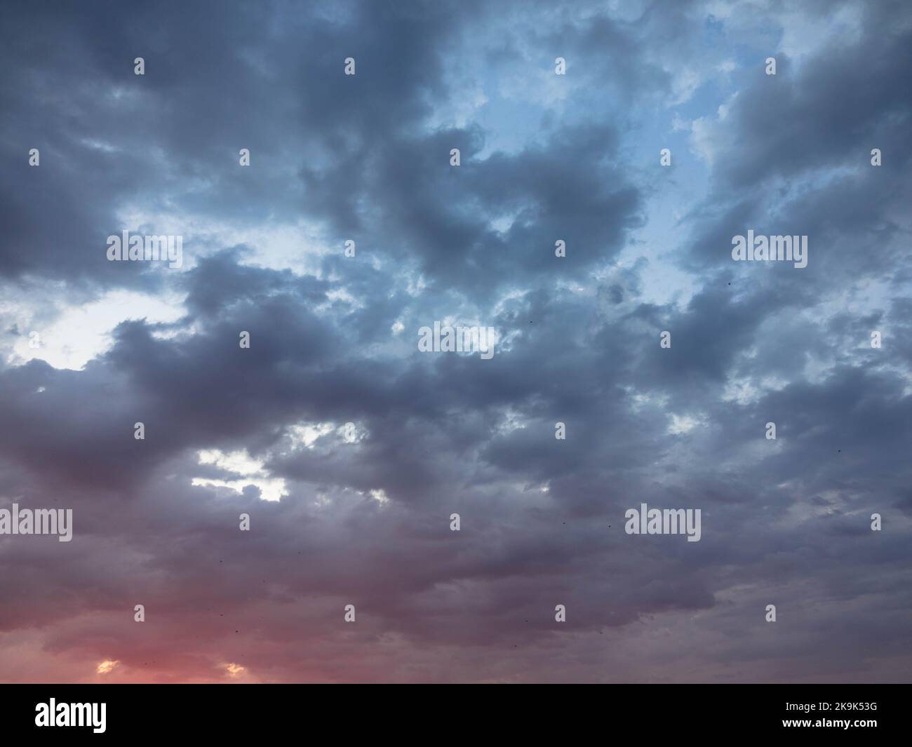 Dramatic twilight sky and clouds background. Dark purple natural sky. Dark clouds, storm and rain. Weather and nature concept. Plenty space of text. Stock Photo