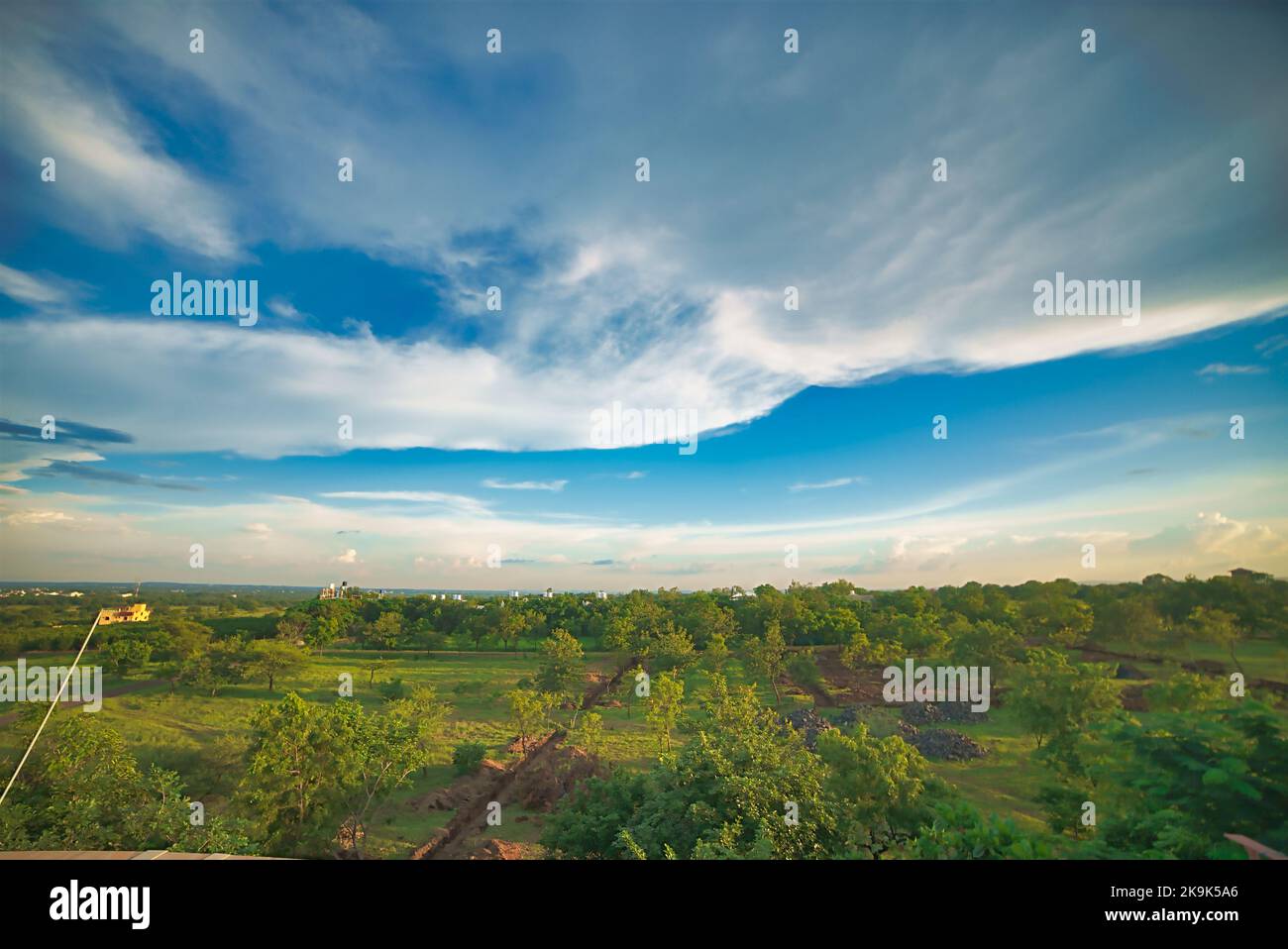 Dramatic scenic landscape background screen saver clouds green fields wide open spaces forest plantations outdoors rural  India Stock Photo
