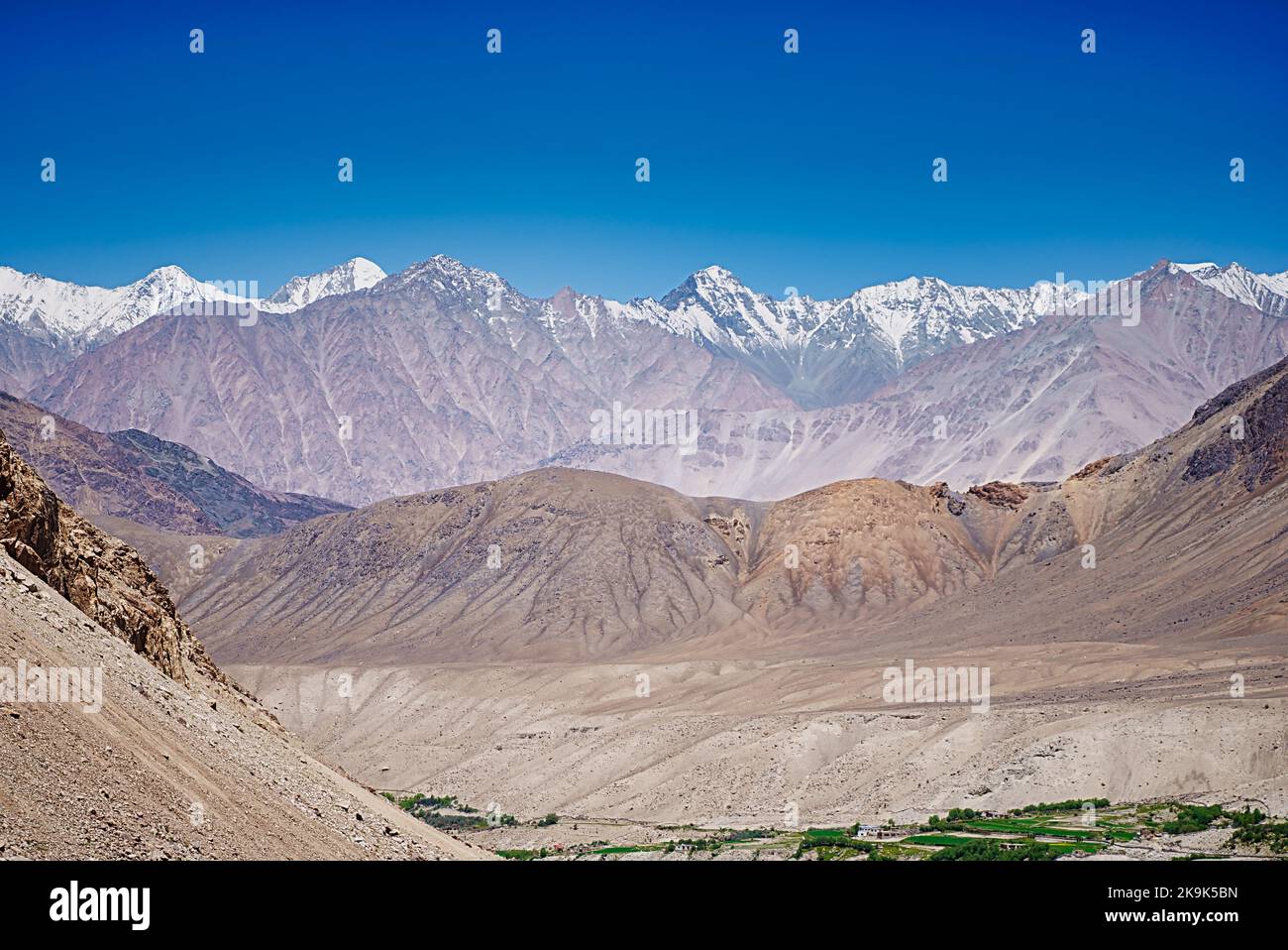 Wide vista view of barren mountains and Leh Valley seen from Khardung la at 18000 feet altitude with the Saser Kangri Peaks. Stock Photo