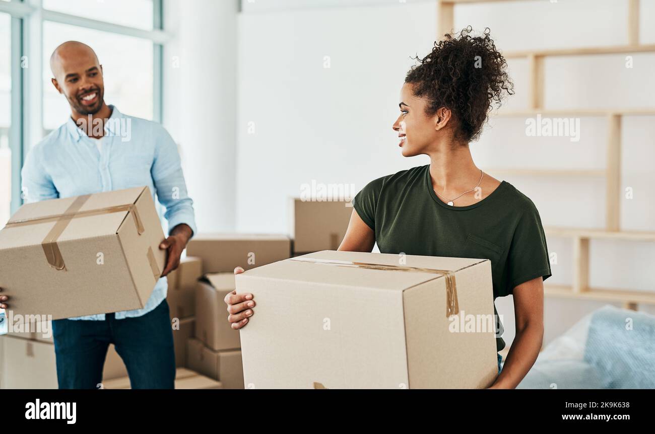 Moving around, but never without each other. a couple young carrying boxes while moving house