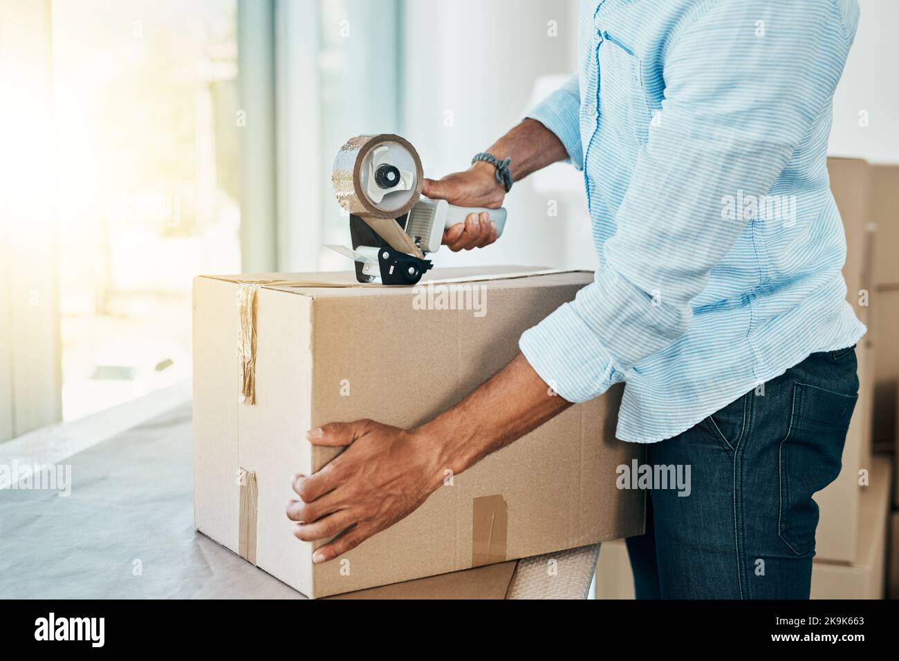 All packed and ready to move on. Shot young man sealing a box while