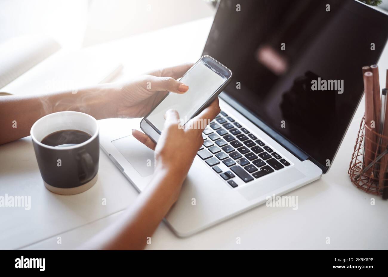 Life of a designer, contacting clients from multiple devices. Closeup shot of an unrecognizable female designer using a cellphone in her home office. Stock Photo