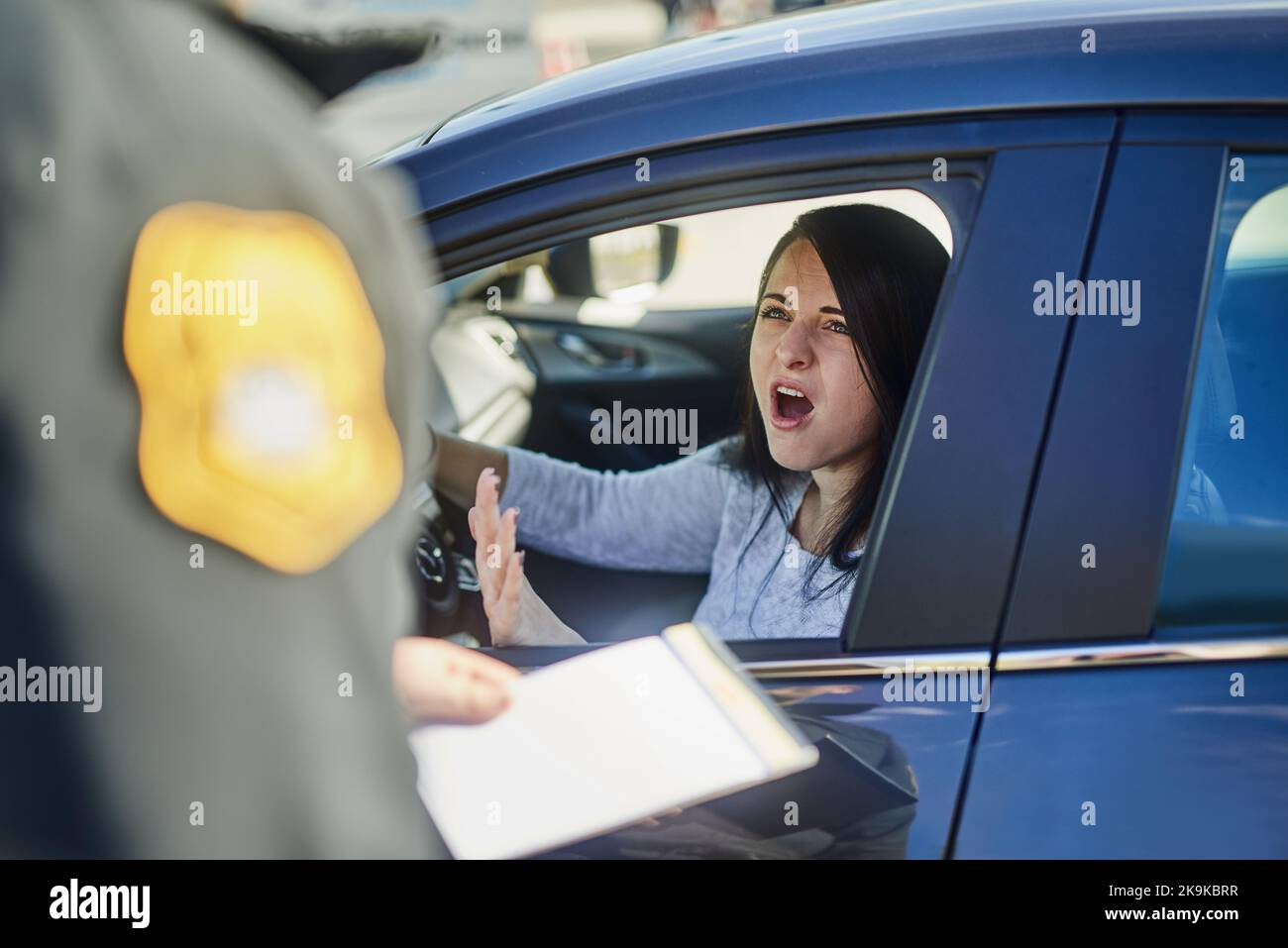 This is ridiculous. an unrecognizable male traffic officer issuing a ticket to a female civilian at a roadblock. Stock Photo