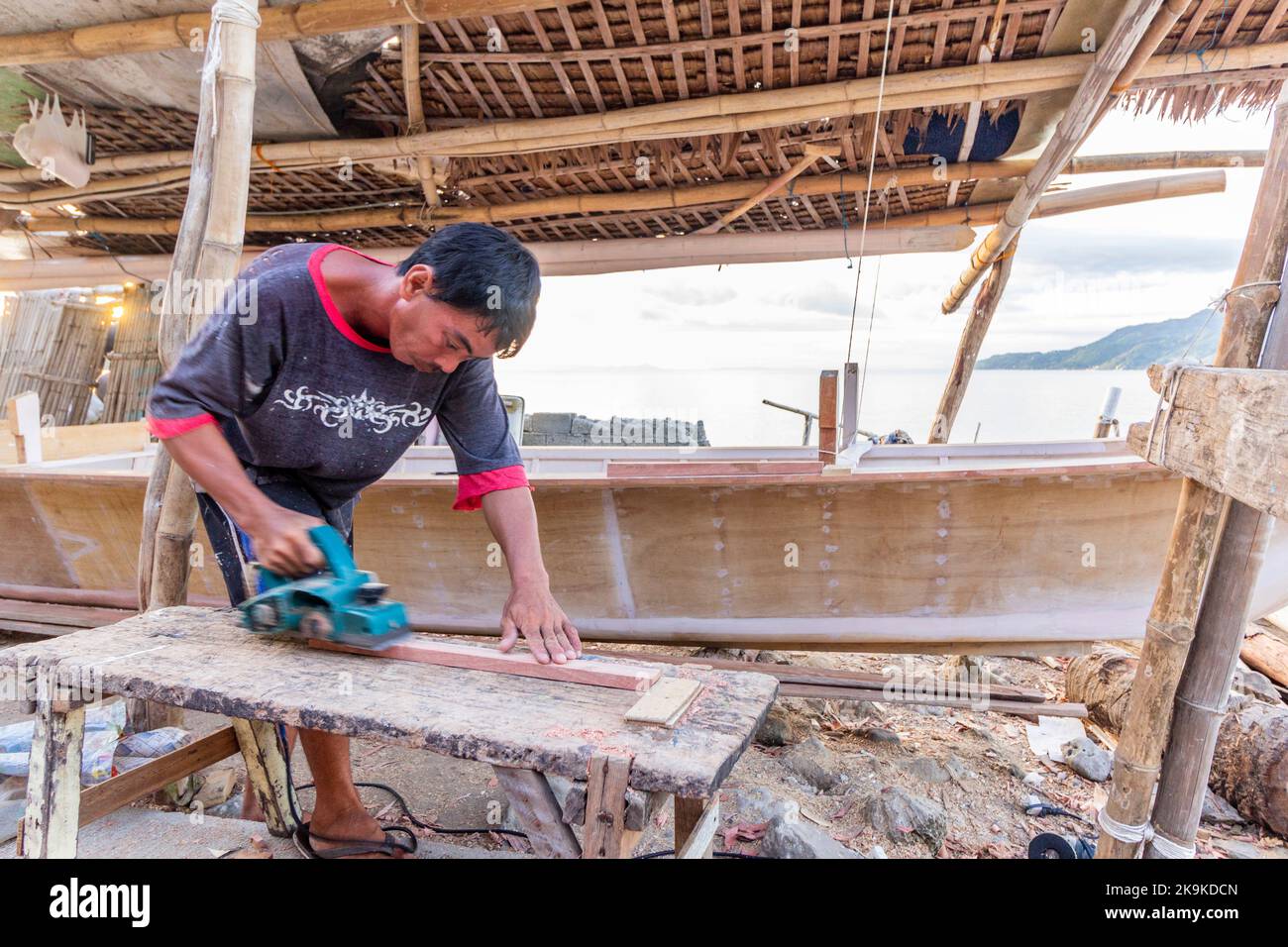 A boat builder using a power planer in Batangas, Philippines Stock Photo