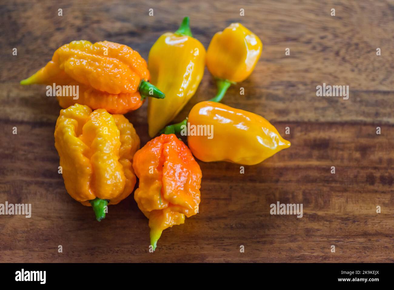 many yellow very sharp habaneros on a wooden table detail view Stock Photo