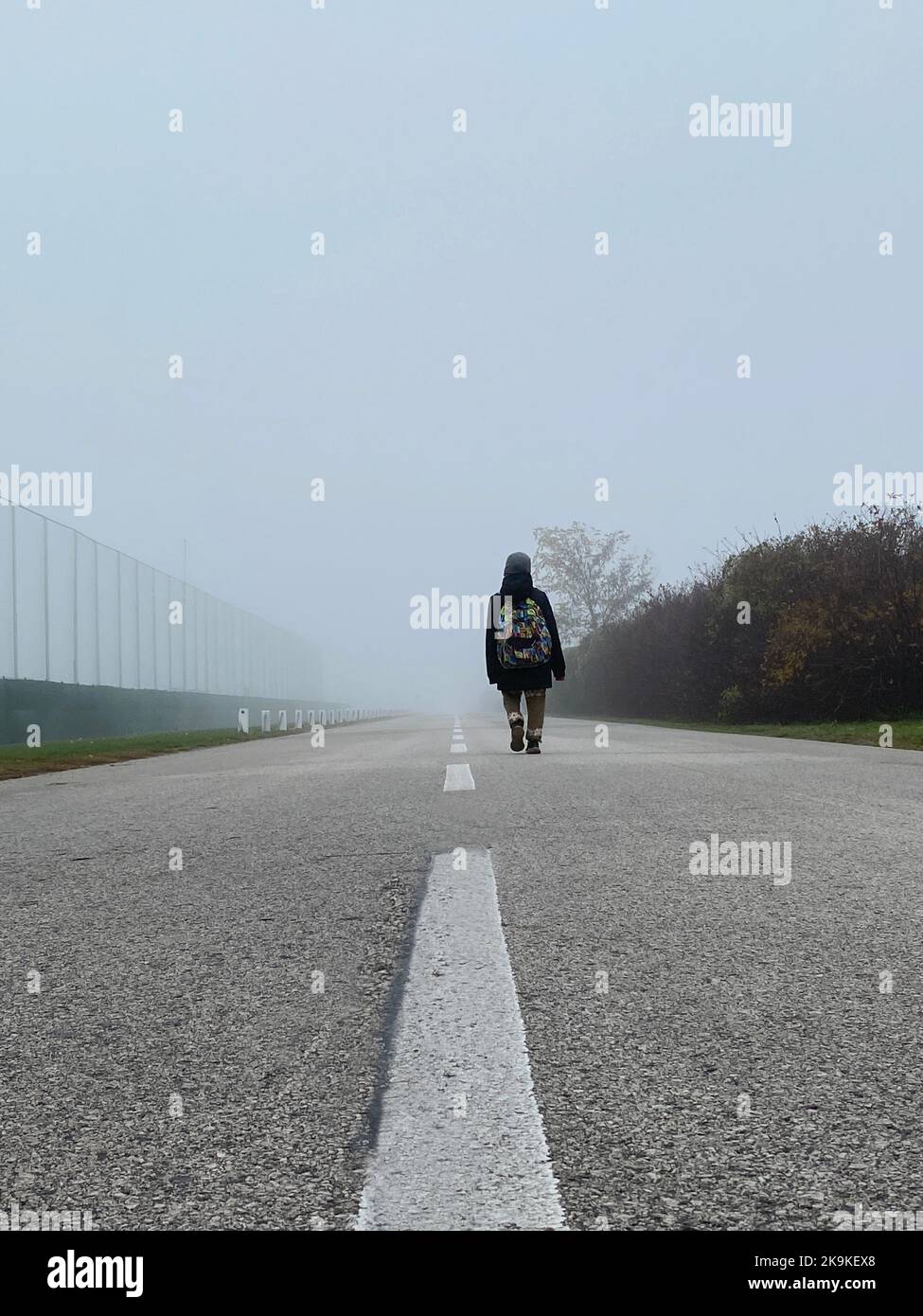 9 years old boy with backpack walking alone on the road in winter