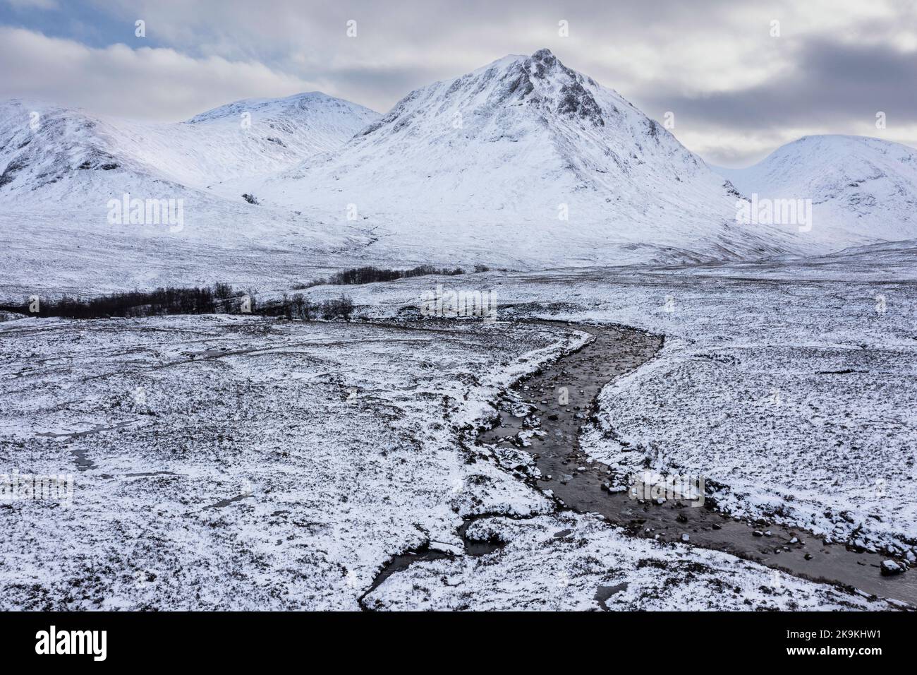 Stunning aerial drone landscape image of Stob Dearg and Glencoe in Scottish Highlands during deep snowfall and beautiful blue skies Stock Photo