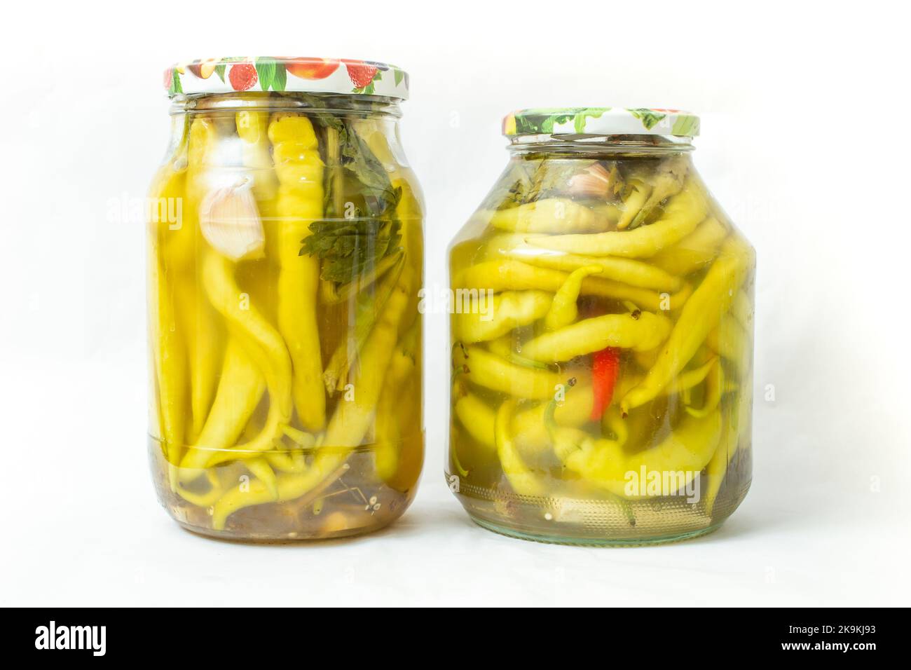 Pickled green peppers in 2 clear glass jars, isolated on white