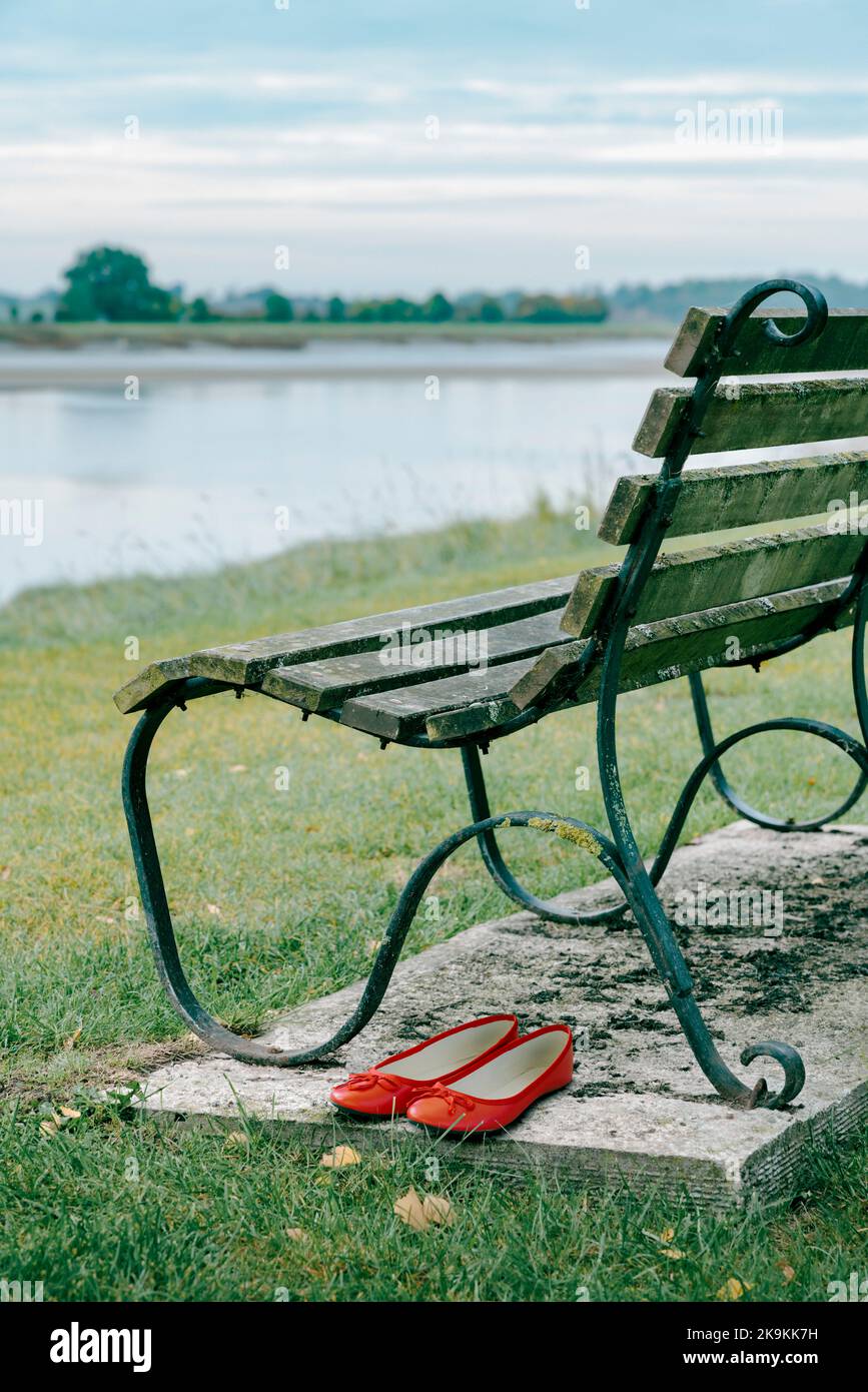 Pair of red shoes and park bench. Stock Photo