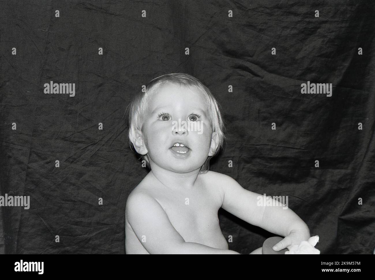 Portrait of a one year old baby boy against a dark background. Stock Photo