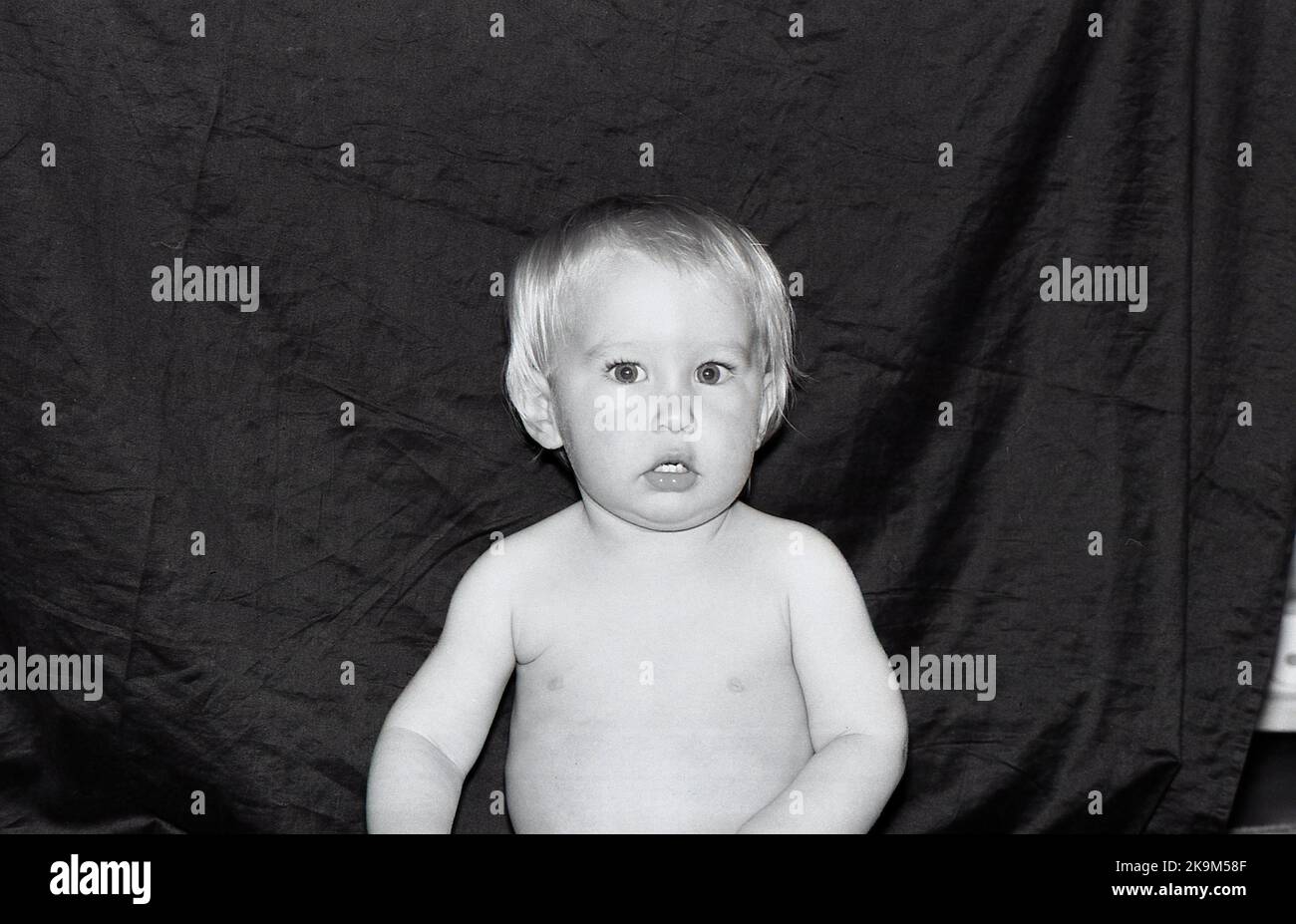 Portrait of a one year old baby boy against a dark background. Stock Photo