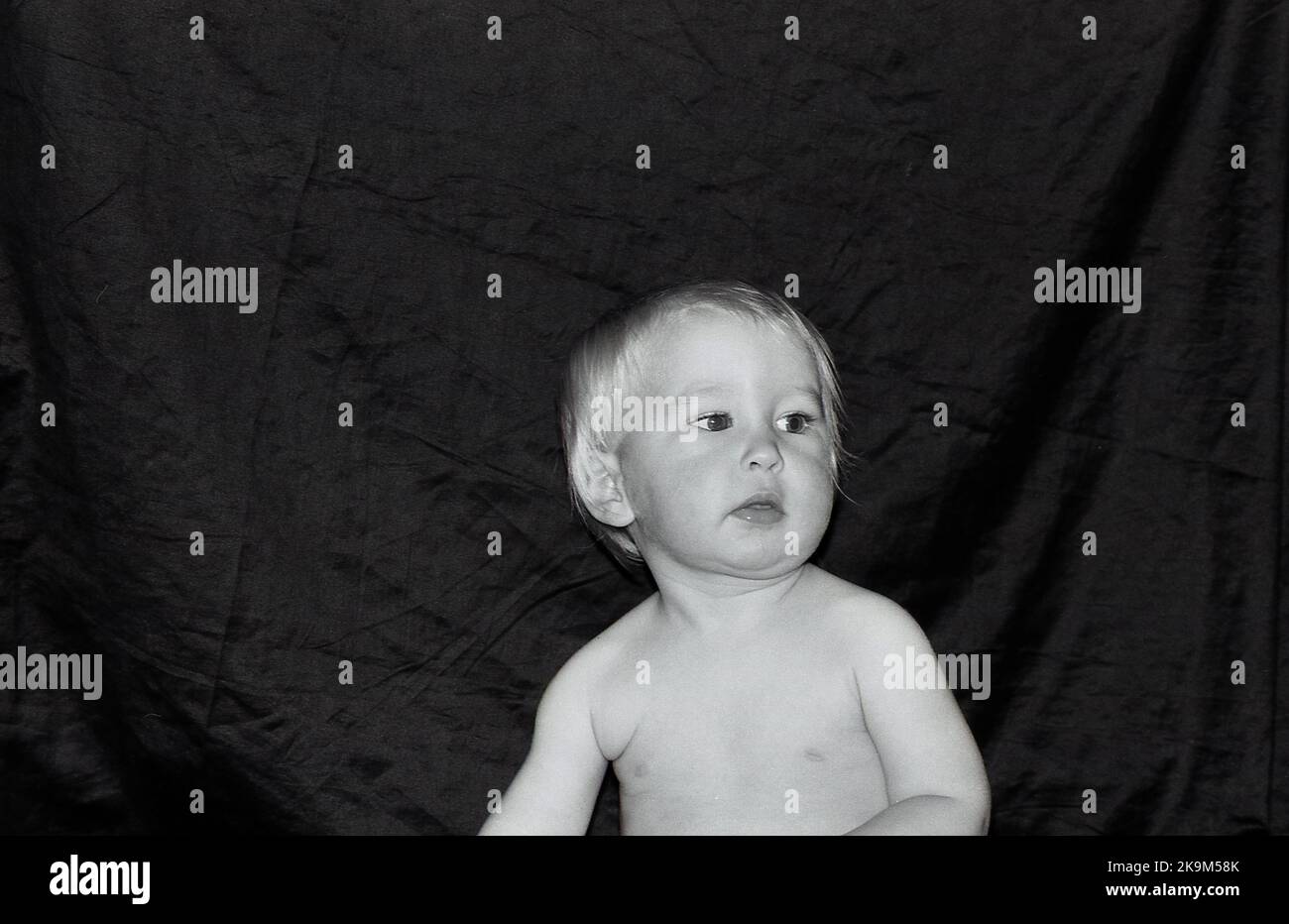 Portrait of a one year old baby boy against a dark background. Stock Photo