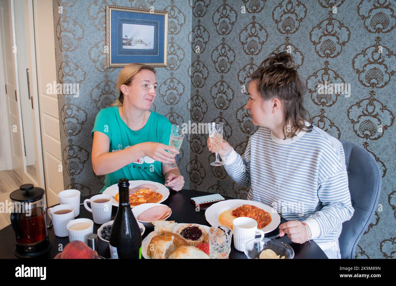 St. Petersburg, Russia, August 2021: Young women in pajamas celebrate and drink champagne in crystal glasses on the bruderschaft. Stock Photo