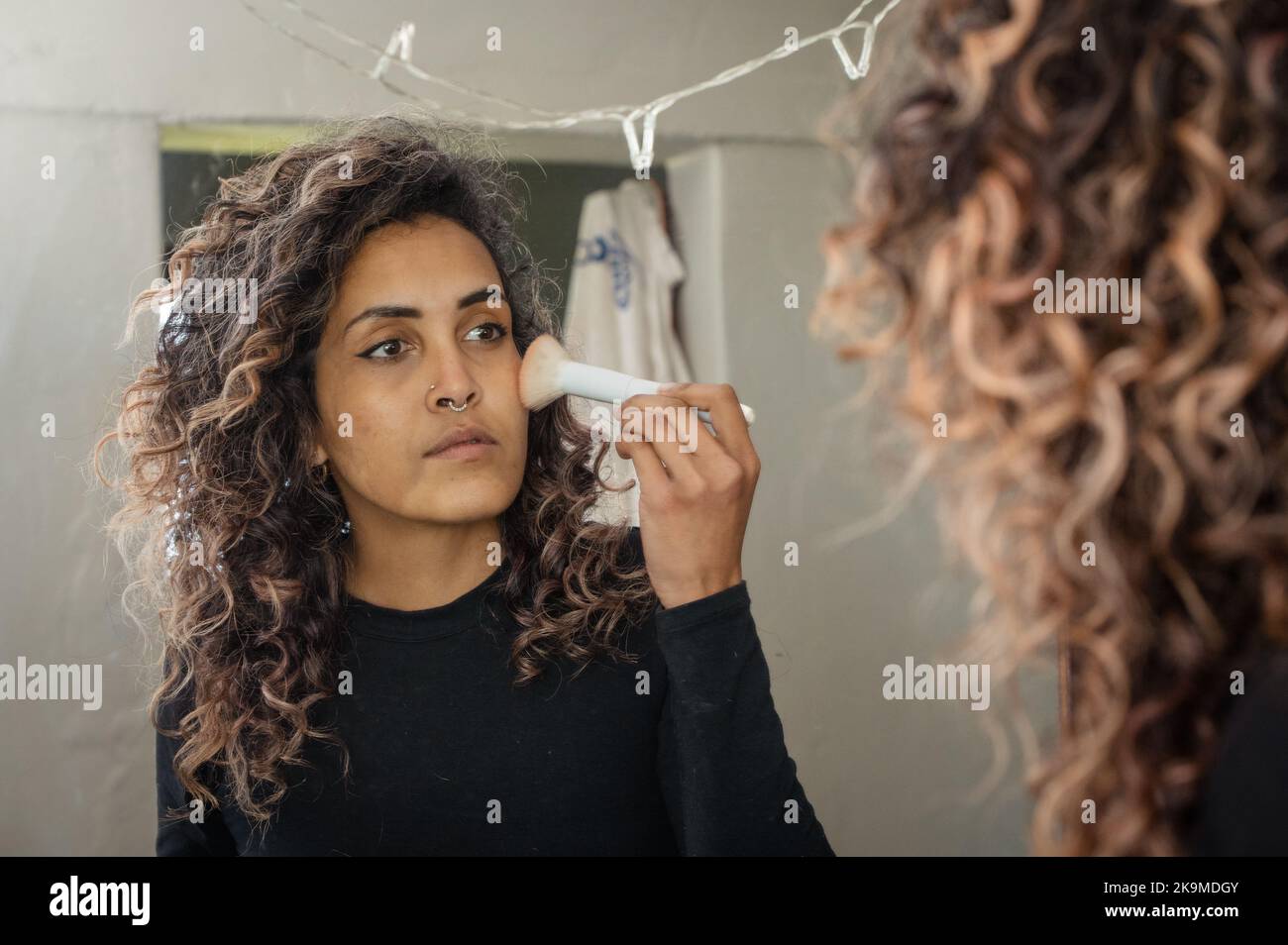 Rear view of woman applying makeup in mirror Stock Photo - Alamy