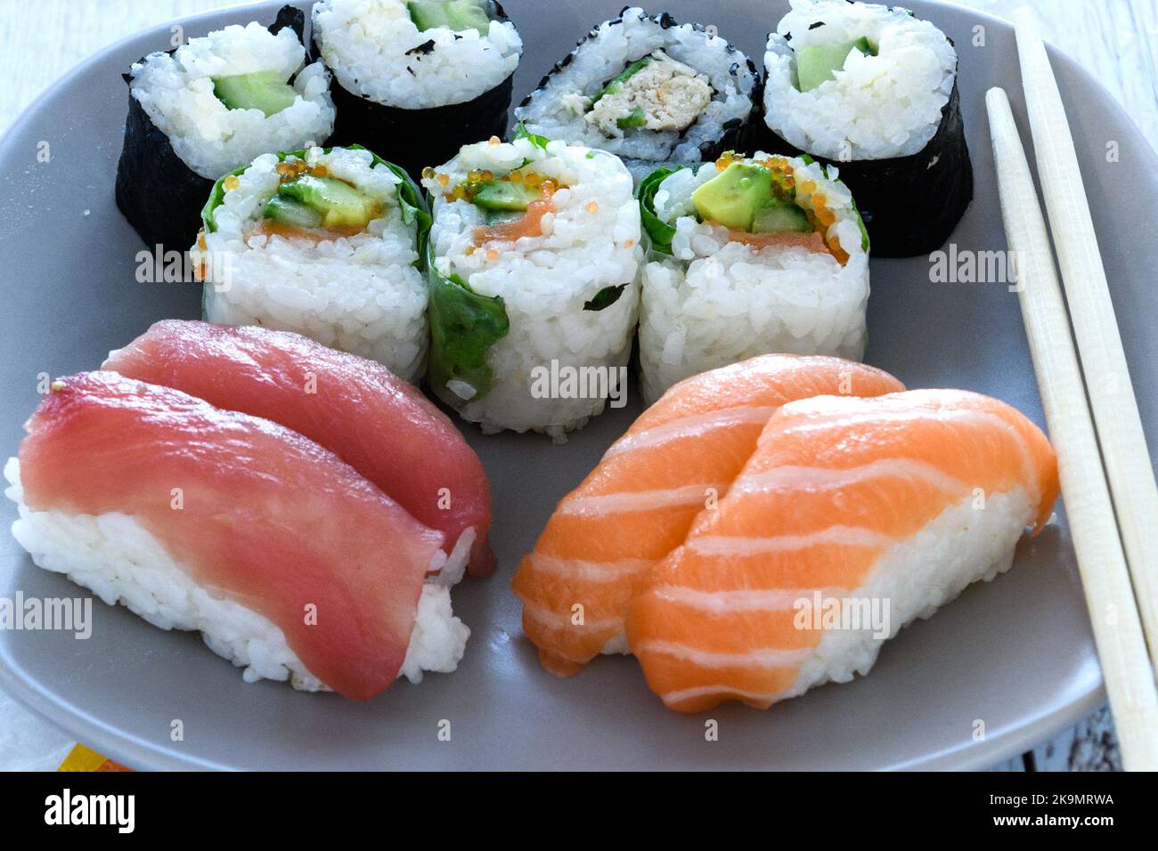 Plate of sushi rolls. Sushi set sashimi and sushi rolls served on wooden plate. Rolls with salmon, eel, tuna, avocado, royal prawn, cream cheese cavia Stock Photo