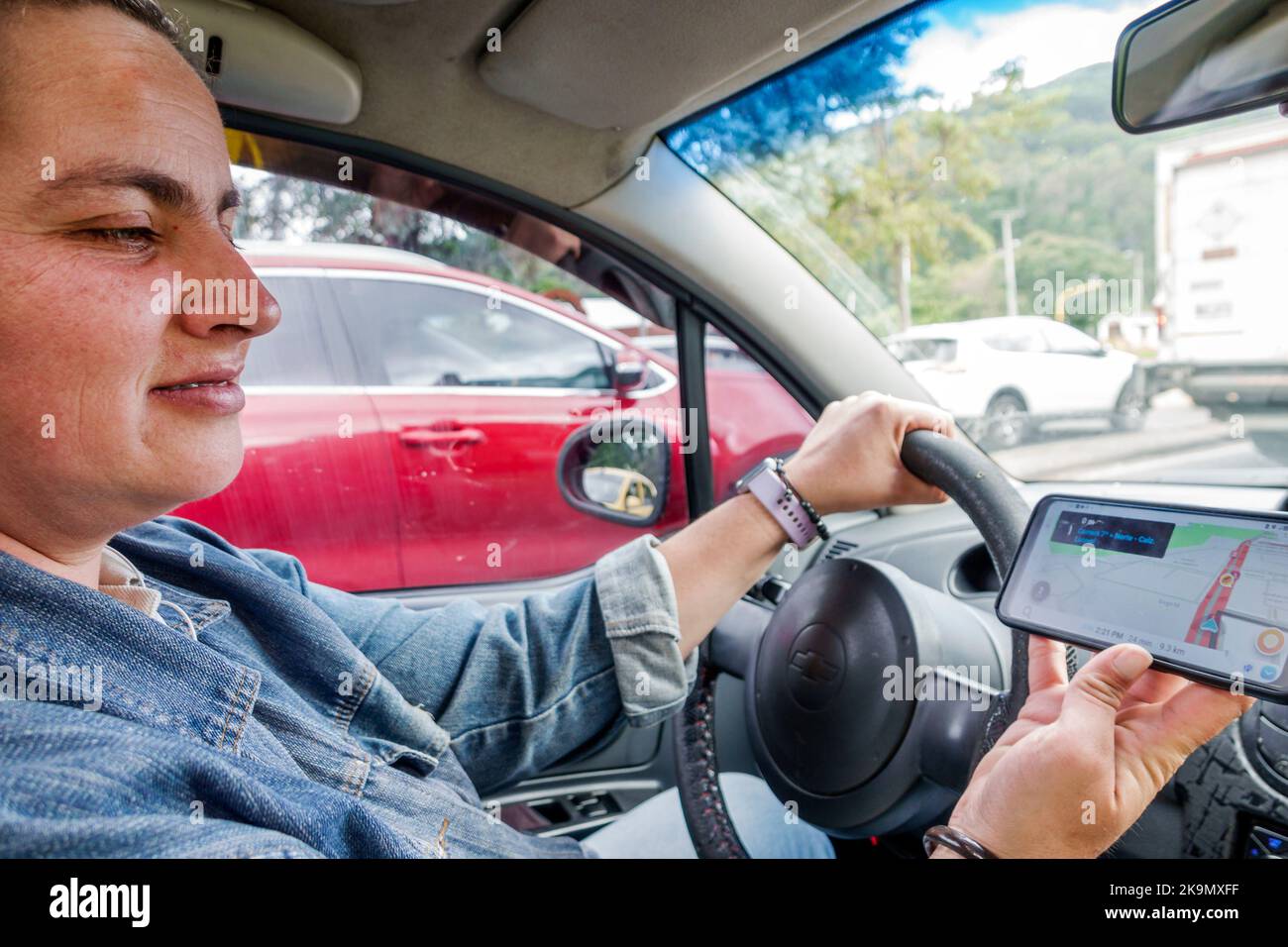 Bogota Colombia,Chapinero Uber driver driving inside interior car vehicle app,woman women female interior inside,smartphone mobile cell phone using re Stock Photo