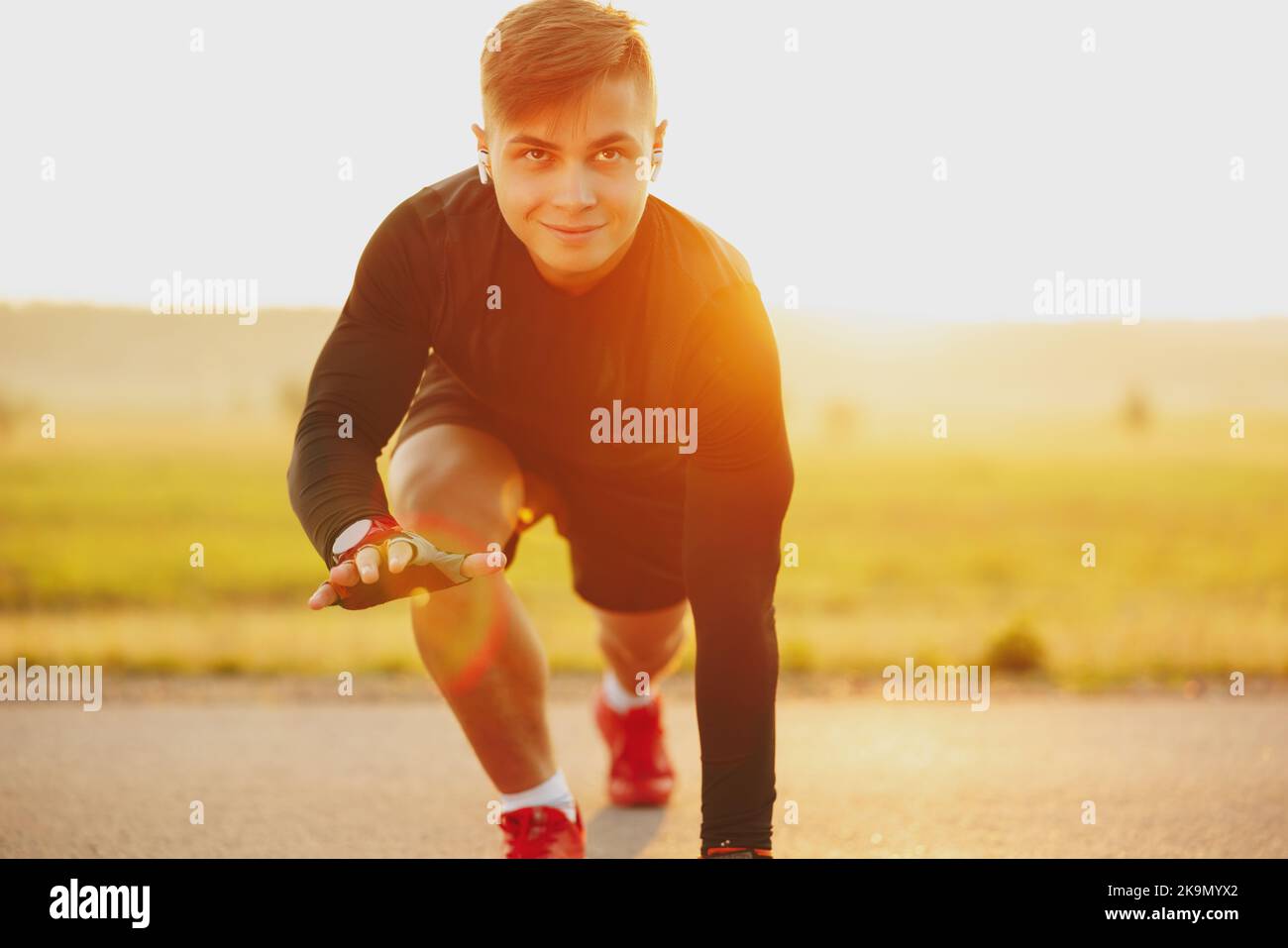 Runner standing in start position outdoors on the street with a ...