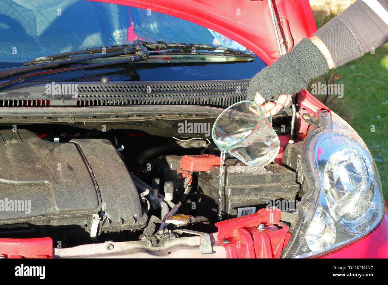 Man topping up the water levels in his radiator and screen wash of his