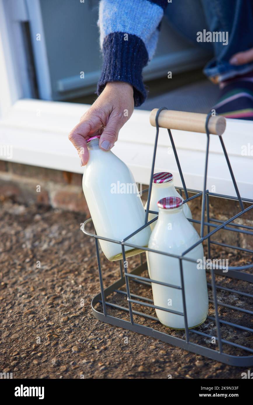 Person Picking Up Bottle Of Milk From House Door Step Stock Photo