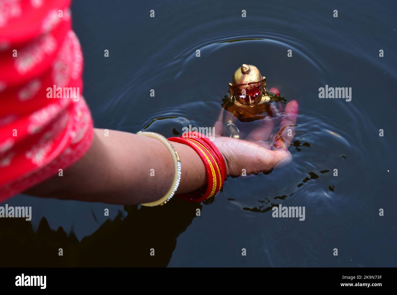 Women Jalabhishek of Laddu Gopal and perform rituals at the Devtal lake on the holy month of Kartik in Jabalpur. Photo By - Uma Shankar Mishra Stock Photo