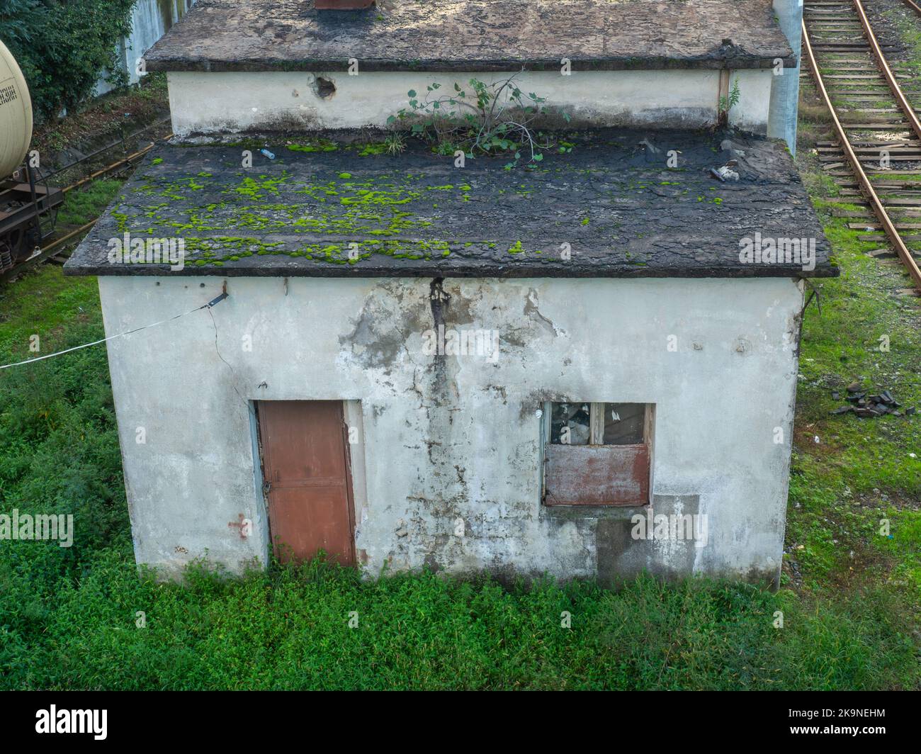 Old abandoned concrete house. Technical structure overgrown with grass. At an abandoned train station. Closed house in ivy. Stock Photo
