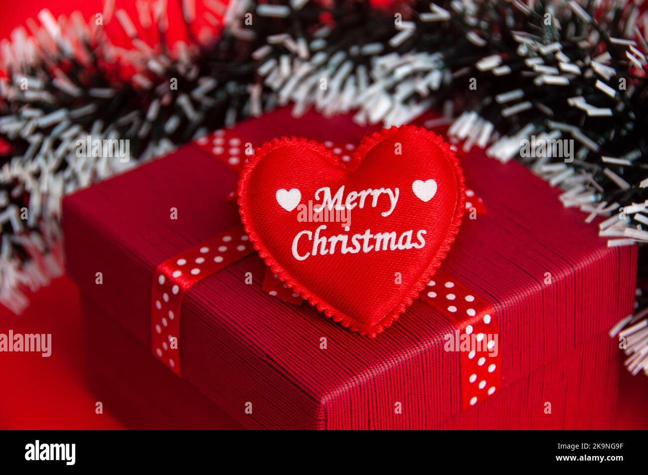 merry-christmas-text-wishes-on-a-heart-shape-on-top-of-red-color