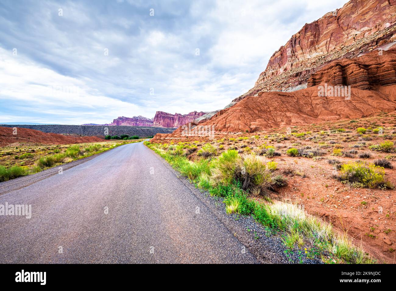 Nature rock formation of red desert canyon with paved road at Capitol Reef National Park, Utah and scenic blue sky with clouds Stock Photo