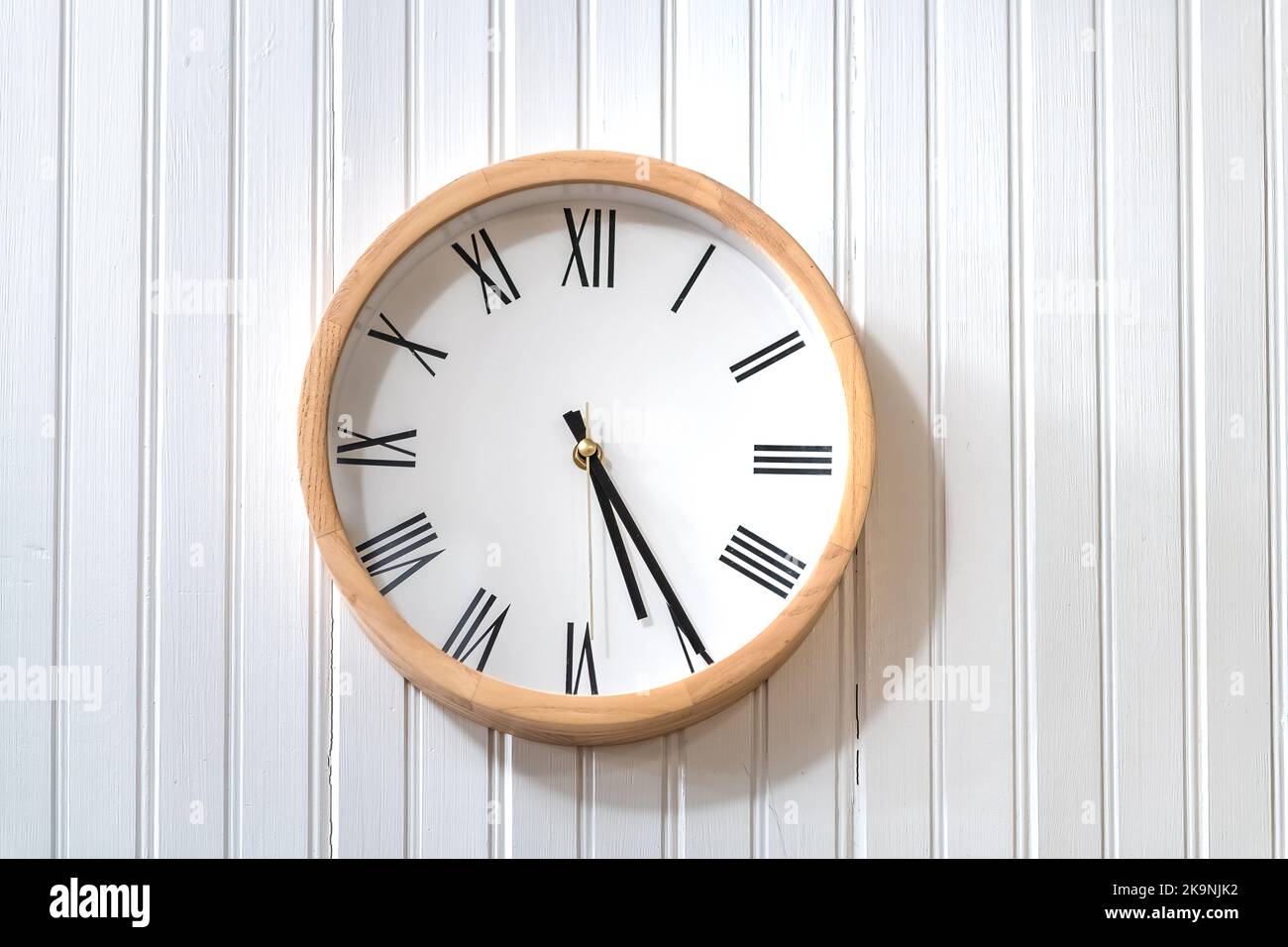 Round modern wooden white and black clock on house home wall with five oclock hour simple