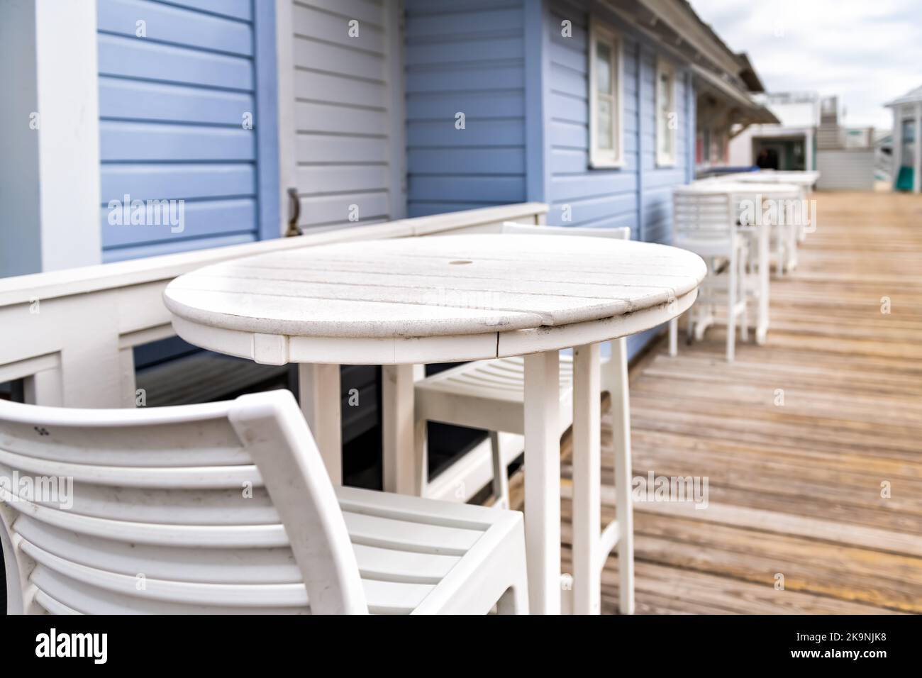 Seaside with empty chairs bar stools, round wooden tables in winter Florida Panhandle city town beach village with white blue architecture restaurant Stock Photo
