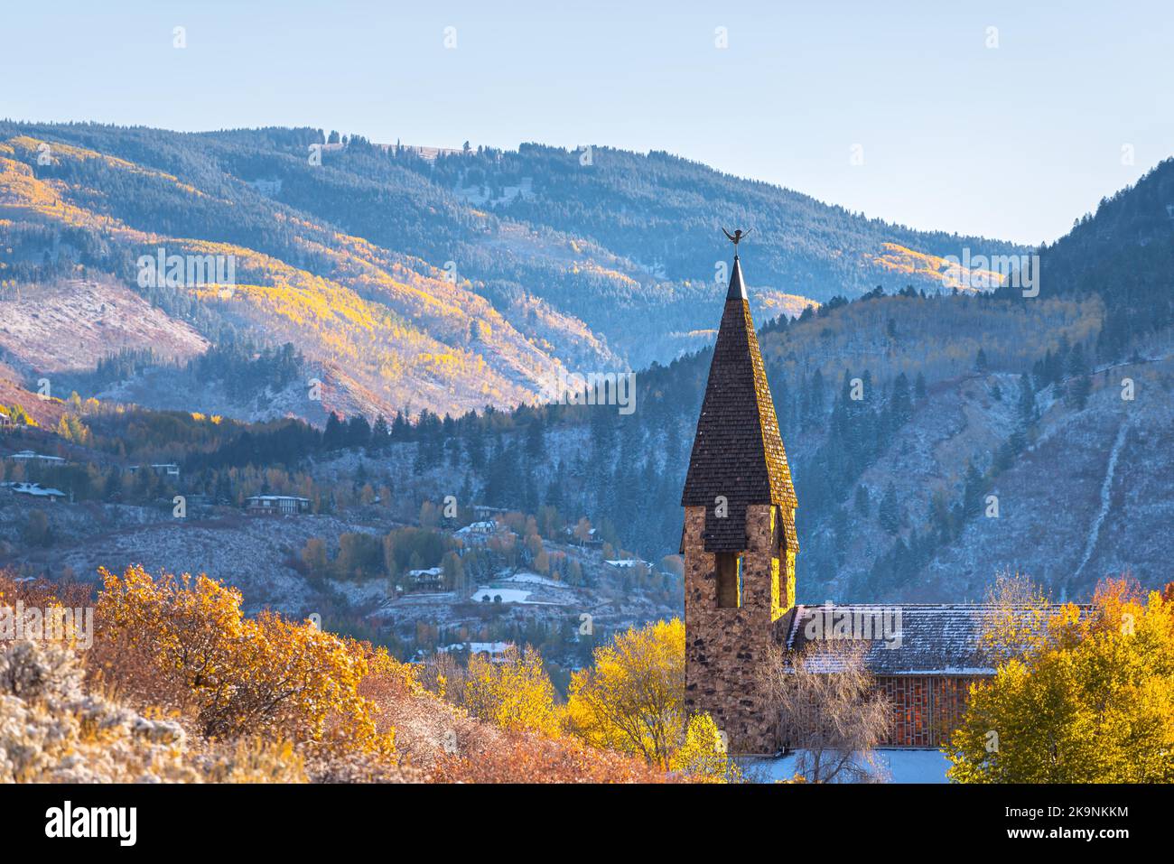 Aspen, Colorado ski resort town city chapel church bell tower building in autumn fall colorful foliage, early winter with snow in mountain valley Stock Photo