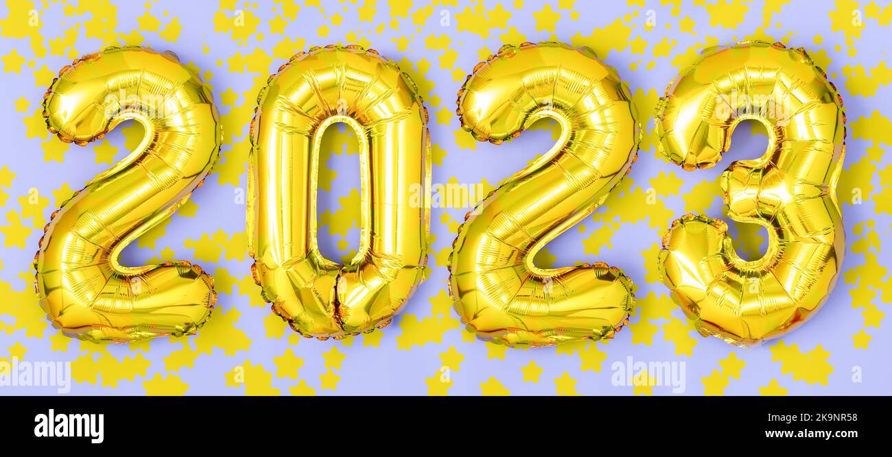 2023 golden foil balloons numbers,  stars confetti, ribbons and bokeh. Top horizontal view copy space new year and holiday concept. Stock Photo