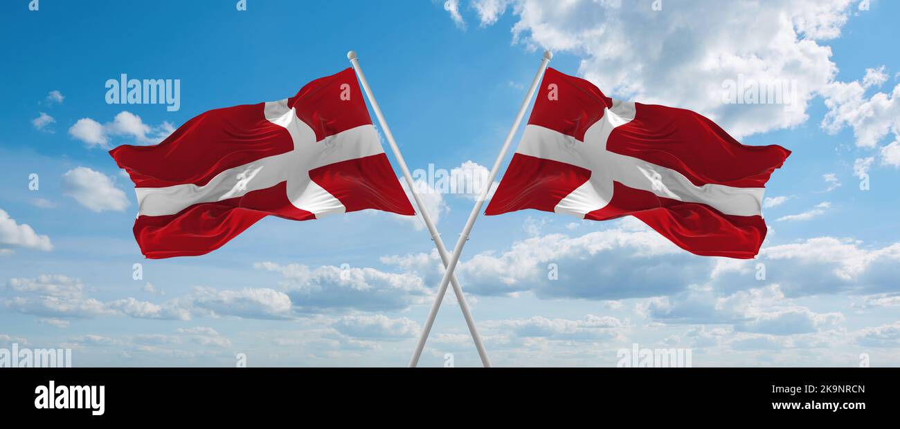 two crossed flags denmark and Denmark waving in wind at cloudy sky ...