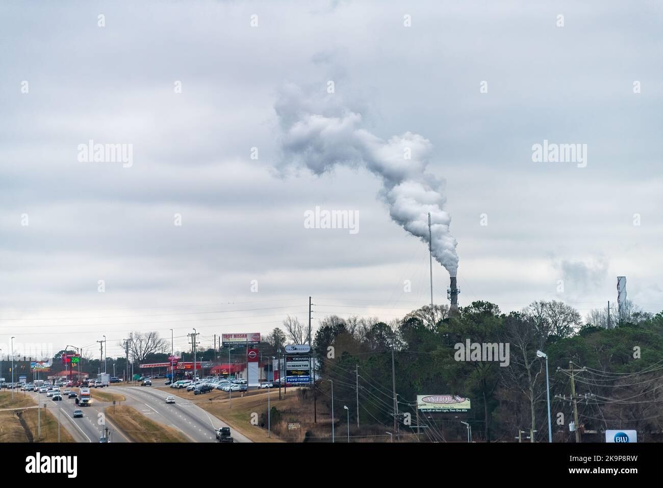 Troy, USA - January 8, 2021: Industrial smokestacks of paper mill factory plant in manufacturing Alabama city with winter cityscape by highway road Stock Photo