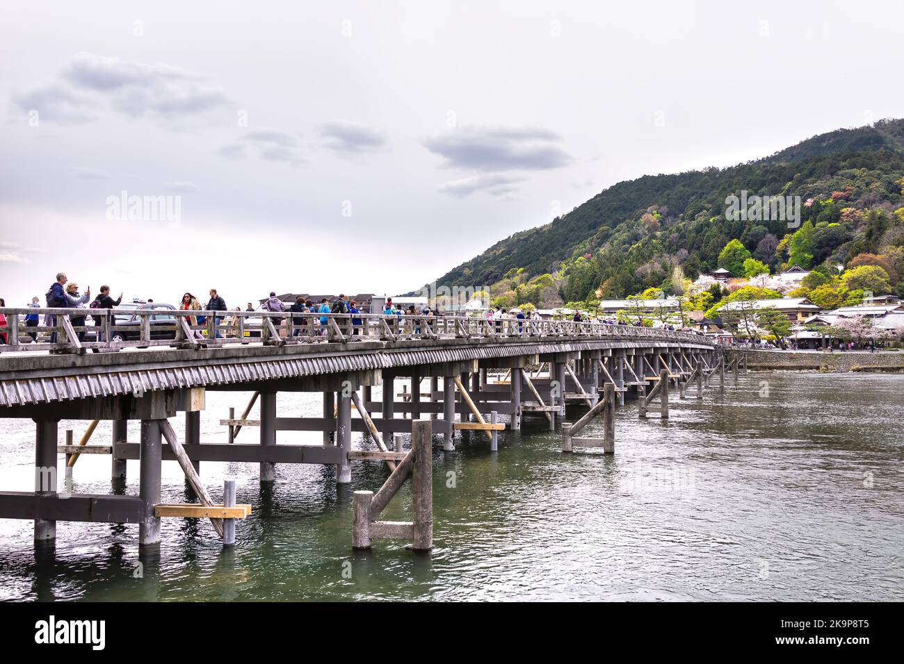 Kyoto, Japan - April 11, 2019: Togetsu-kyo wooden bridge with people taking pictures of Katsura river with Arashiyama park mountains in spring Stock Photo