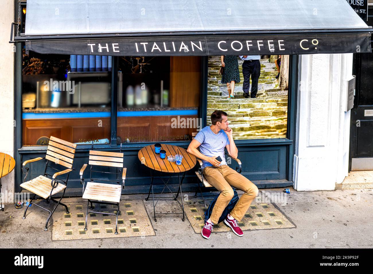 London, United Kingdom - June 22, 2018: High angle view on man sitting at Italian coffee house shop of Caffe Nero on Queen Victoria street sidewalk Stock Photo