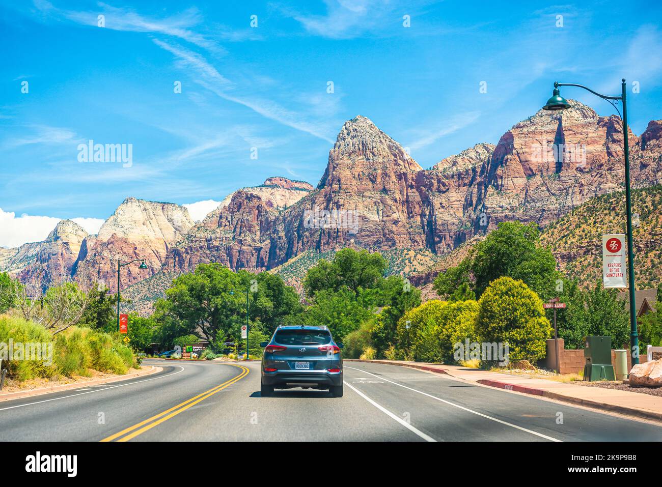 Springdale, USA - August 5, 2019: Mountain canyon town city by Zion national park with cars on main street road with canyons in background in summer Stock Photo