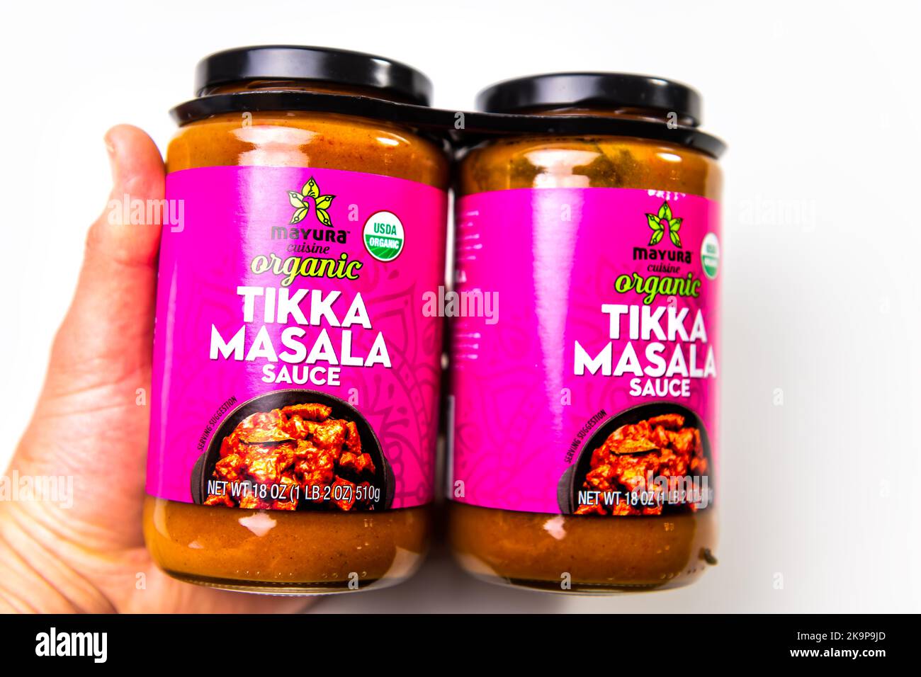Naples, USA - October 21, 2021: Closeup macro hand holding Costco bulk tikka masala organic sauce in bottles jars by Mayura cuisine Indian spice food Stock Photo