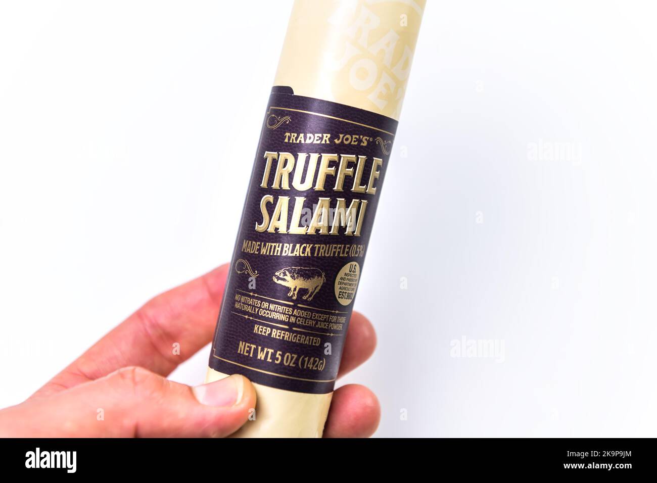 Naples, USA - October 21, 2021: Closeup macro of hand holding black truffle salami sausage by Trader Joe's brand private label with no nitrates food Stock Photo