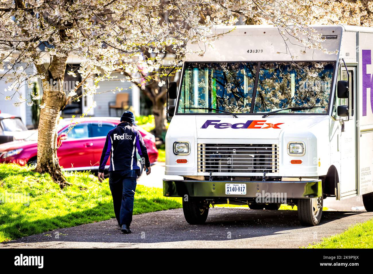 Herndon, USA - April 3, 2021: Fairfax county city, Virginia with residential neighborhood in spring with FedEx truck worker delivering package Stock Photo