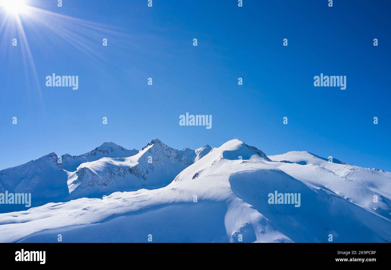 Snow covered mountain peak against the blue sky. Stock Photo