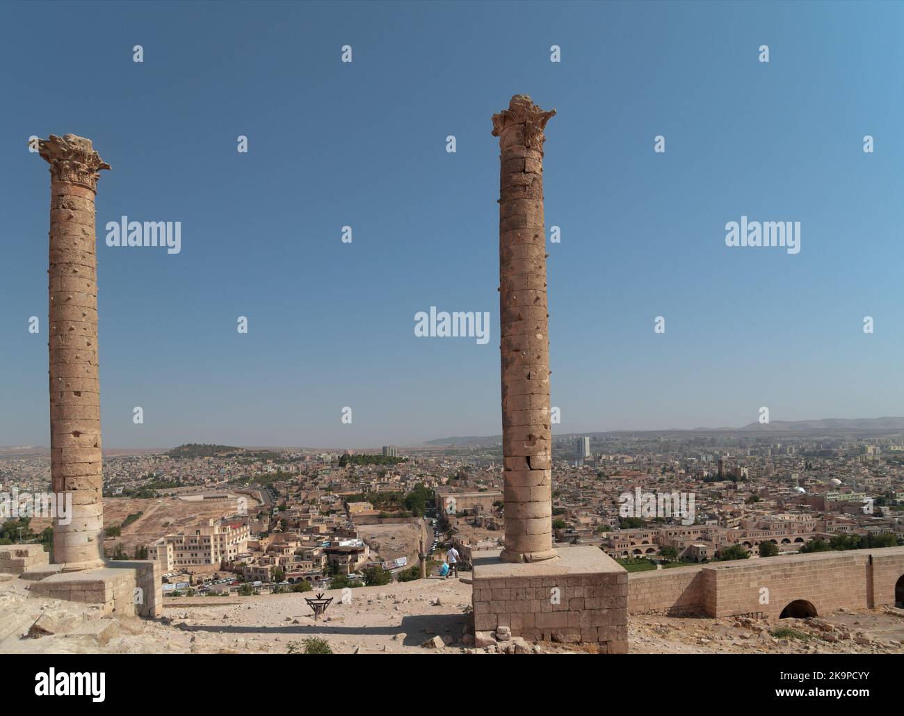 Tourists admire the cityscape under ancient columns in citadel of Urfa, Turkey. The famous dual columns were built by the Abbasids in 814 AD Stock Photo