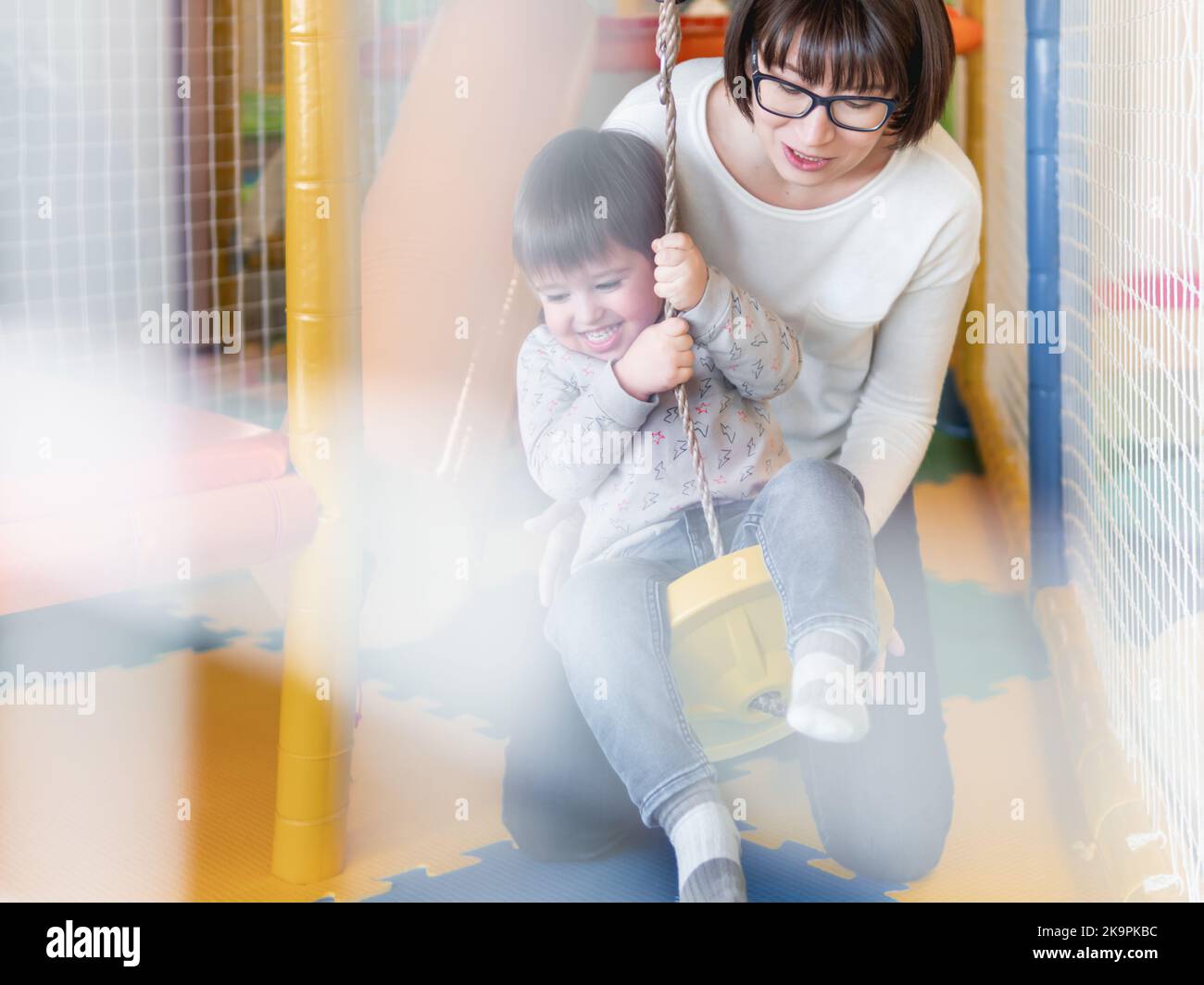Toddler plays on rope swing with his mother or babysitter. Physical ...