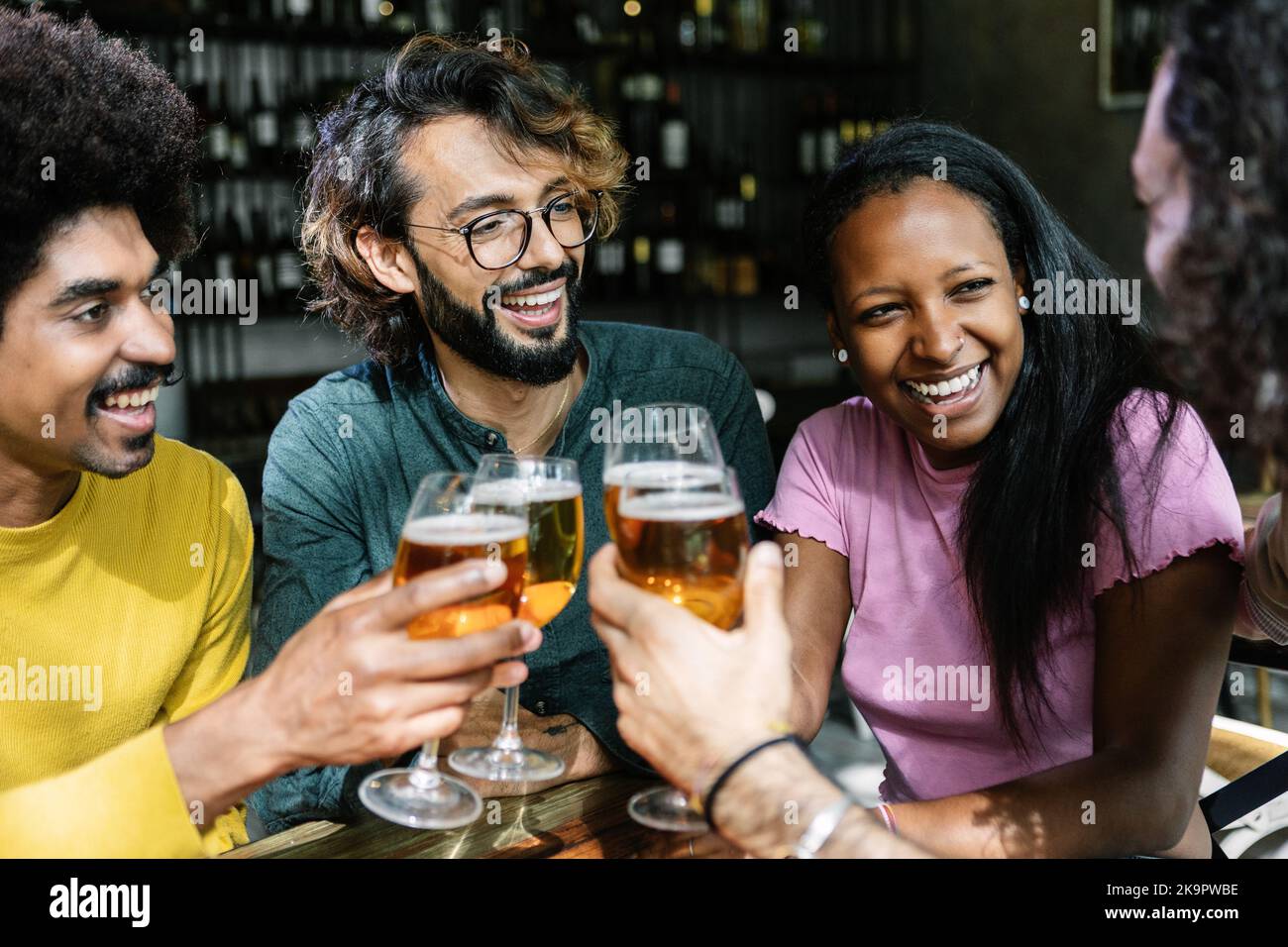 Group of diverse friends enjoying weekend together cheering with beer at bar Stock Photo