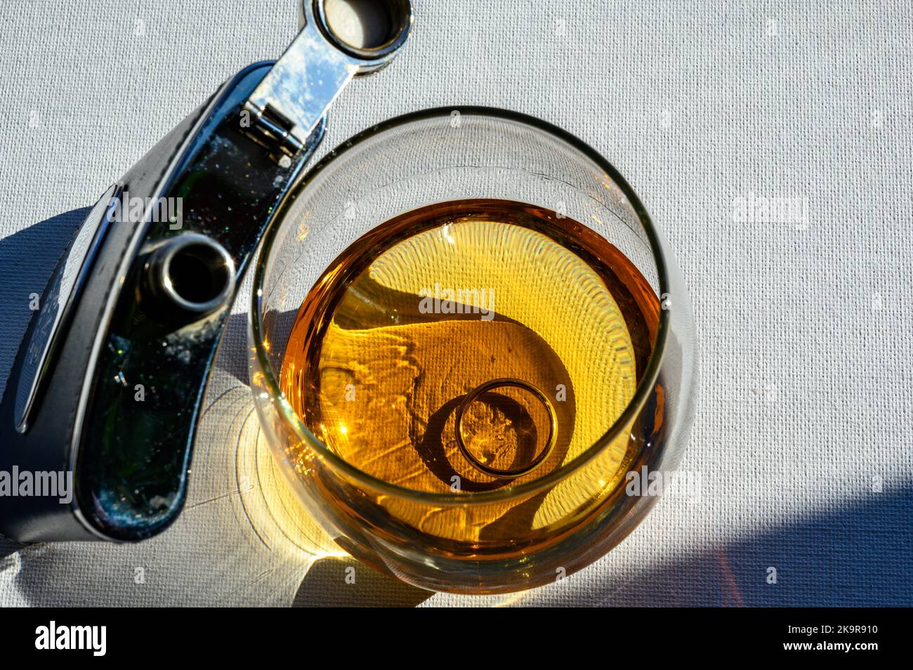 Black and silver whiskey flask next to a glass of amber colored liquid