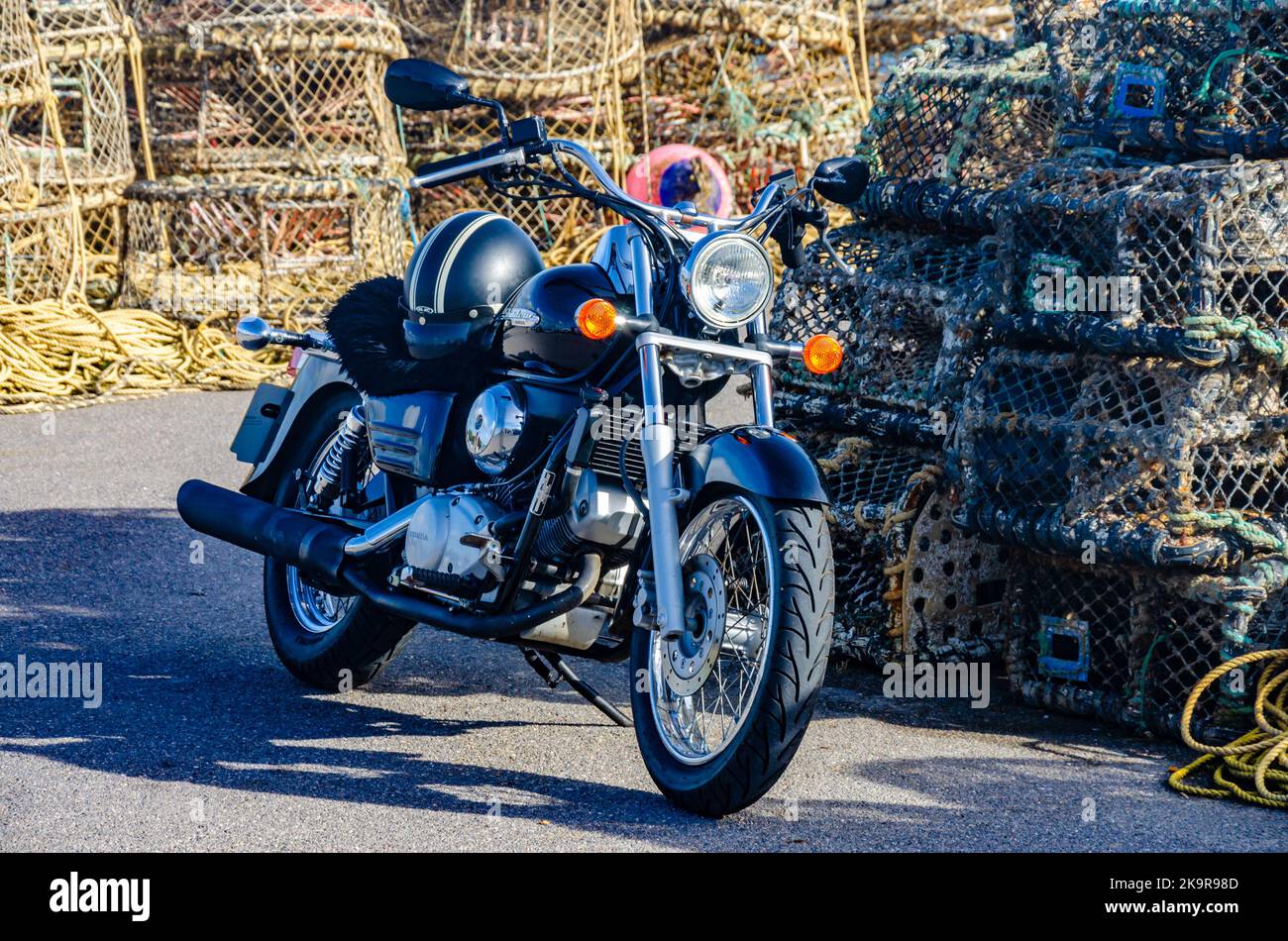 A black Honda Shadow motorbike parked in front of piles of ropes and lobster pots on the quayside at Mudeford near Christchurch in Dorset, UK Stock Photo